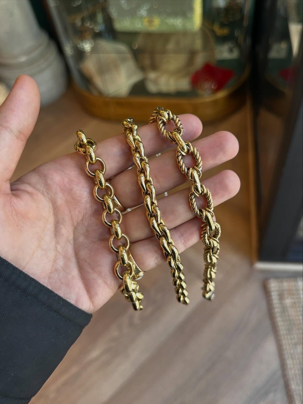 Three chain bracelets laid across an open hand in the shop.