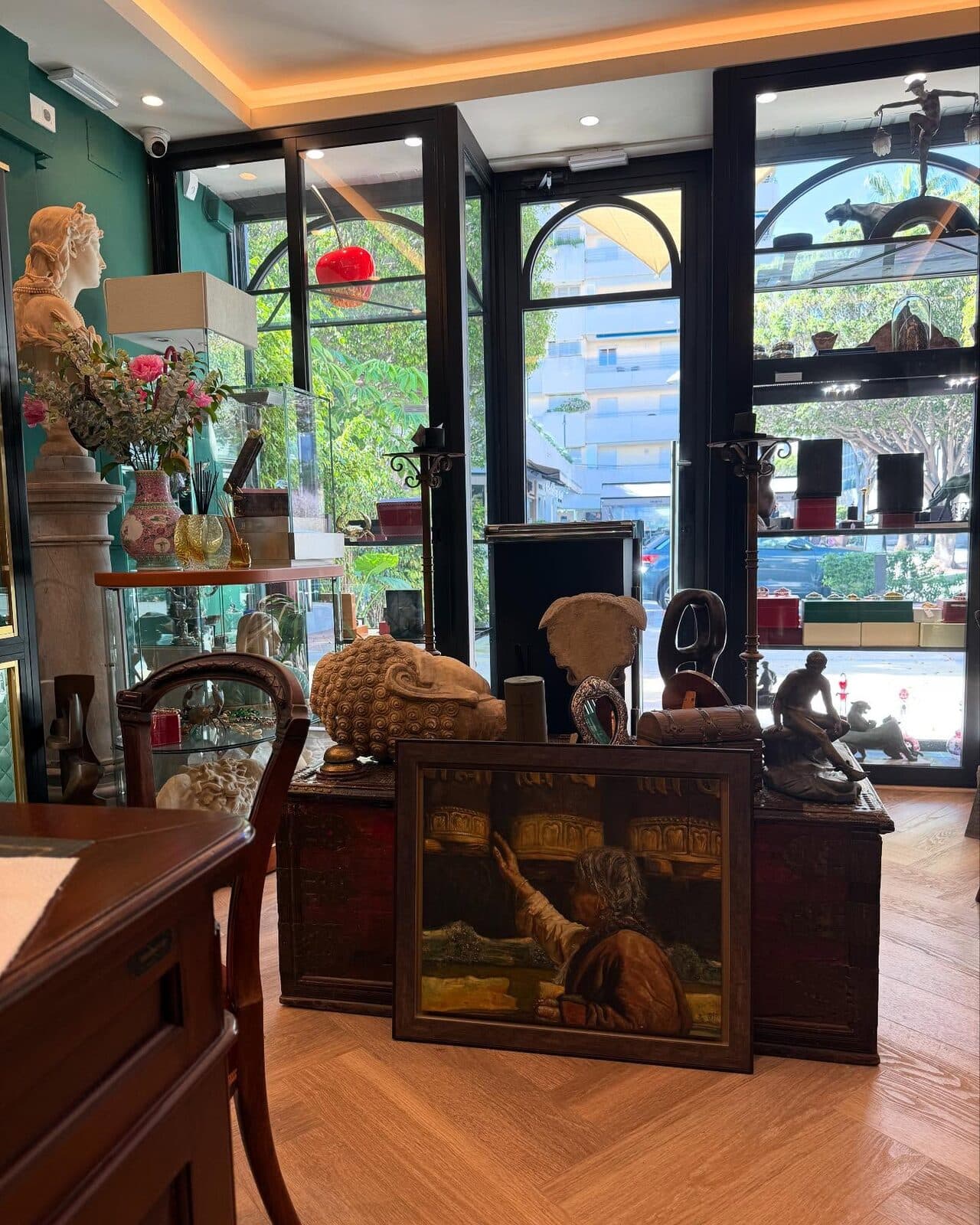 Interior de la tienda de Puerto Banús: vitrinas, antigüedades y un cuadro sobre un suelo en espiga.