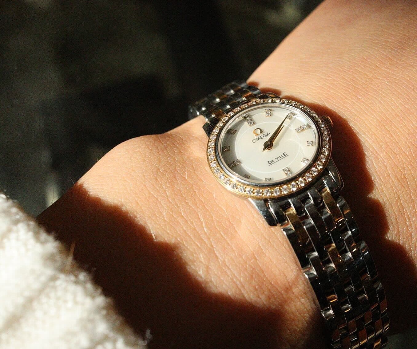 A watch on a wrist in a band of sunlight.