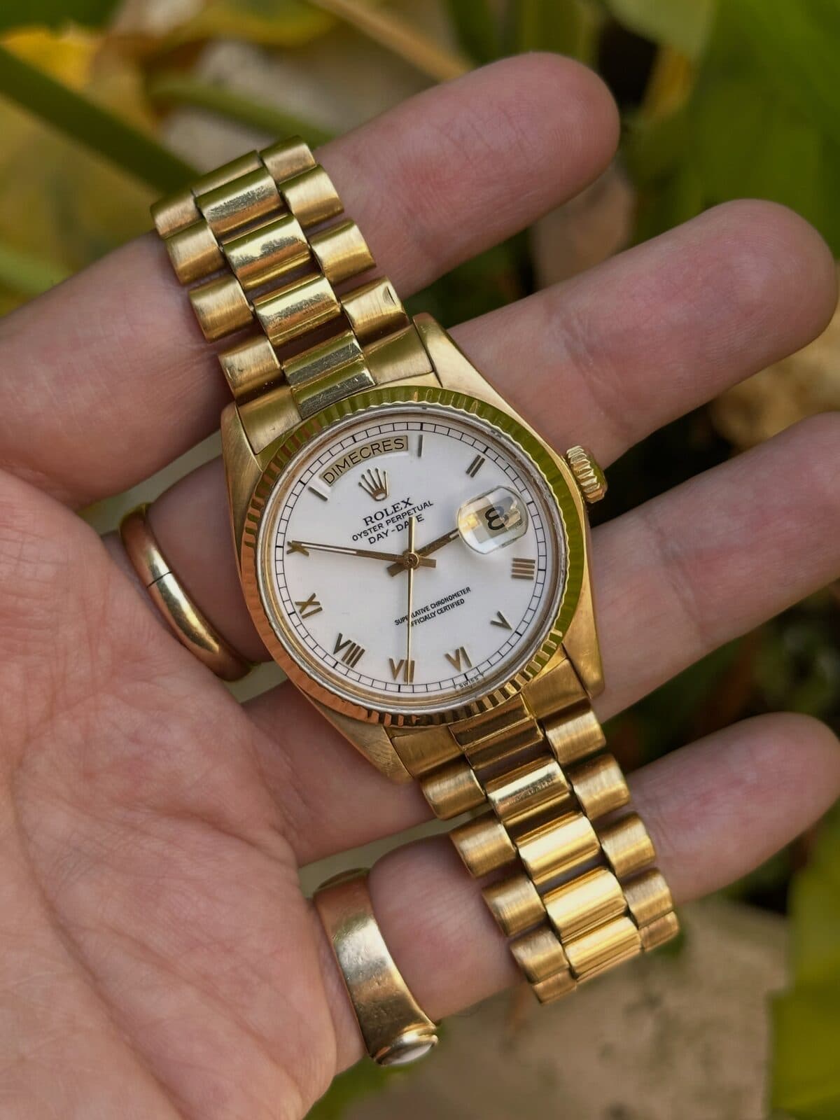 A watch with a white dial in an open palm.