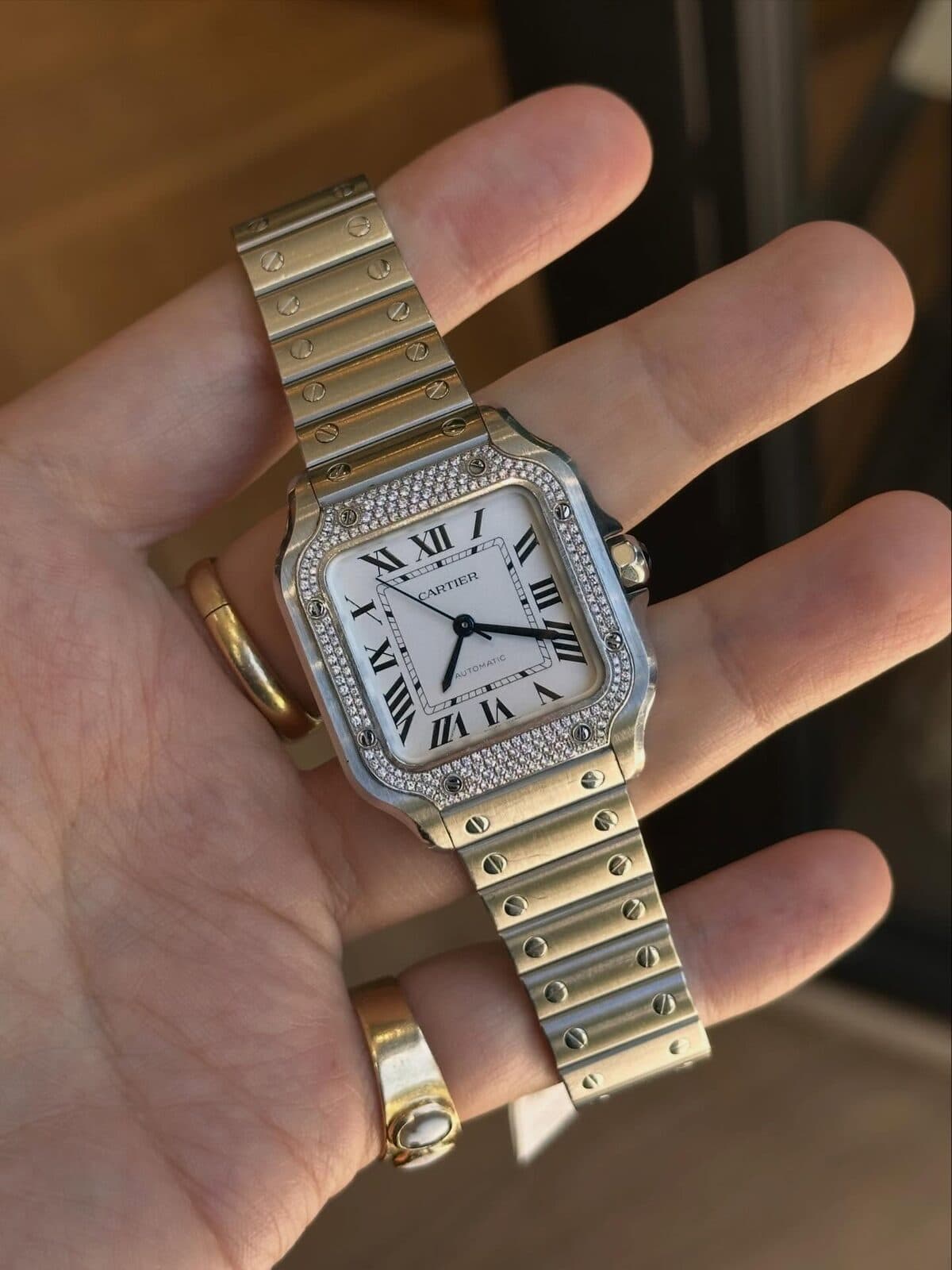 A square watch in an open palm.
