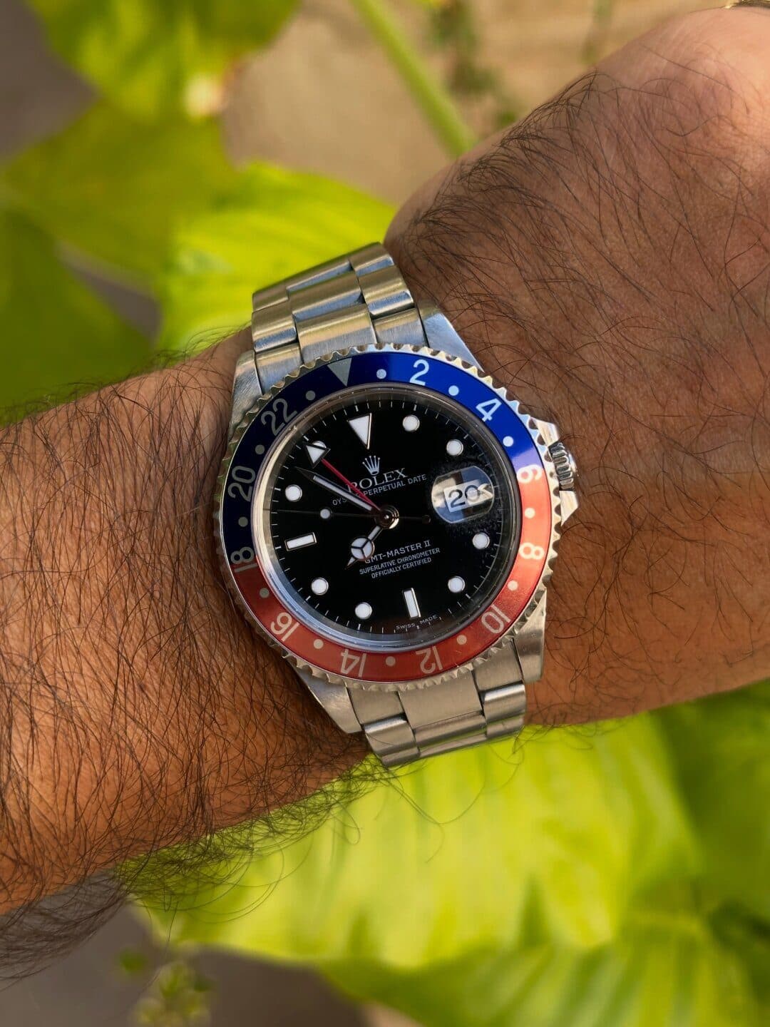 A watch with a red and blue bezel on a wrist.
