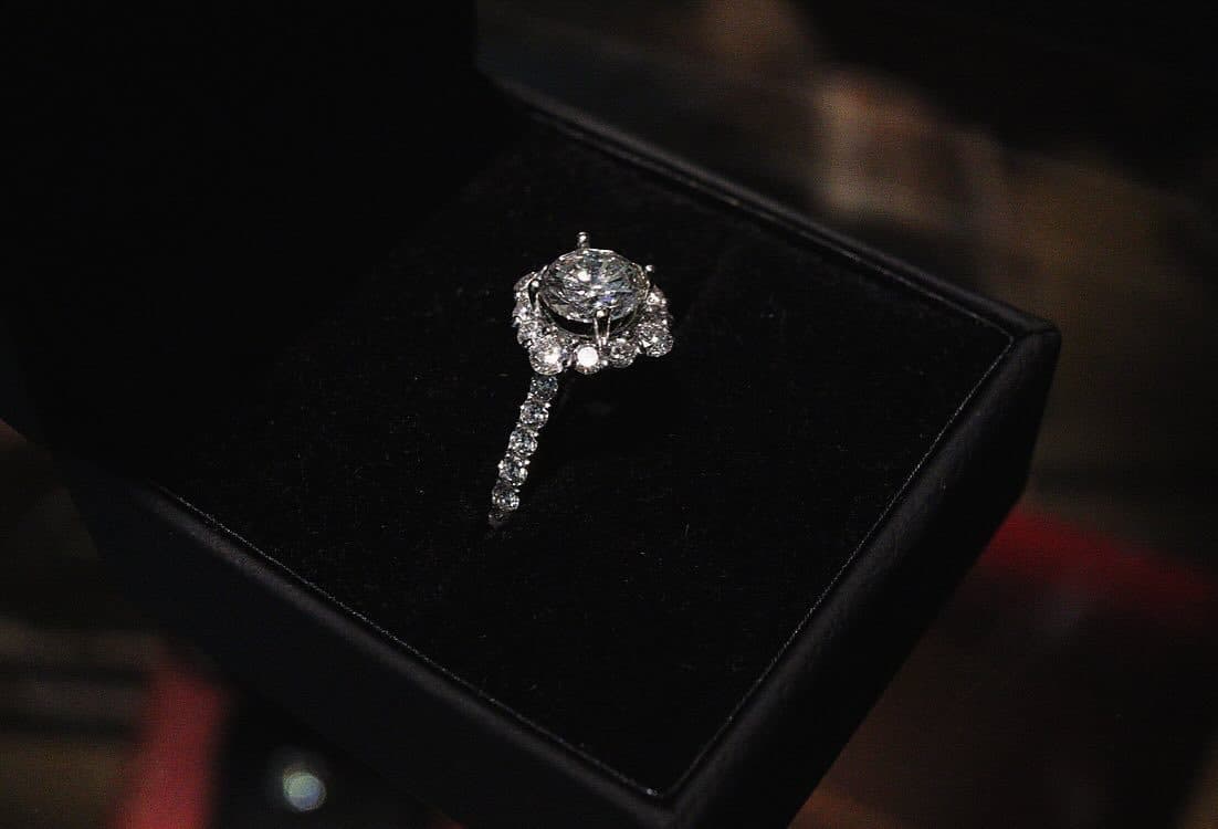 A ring set with clear stones in an open black box.